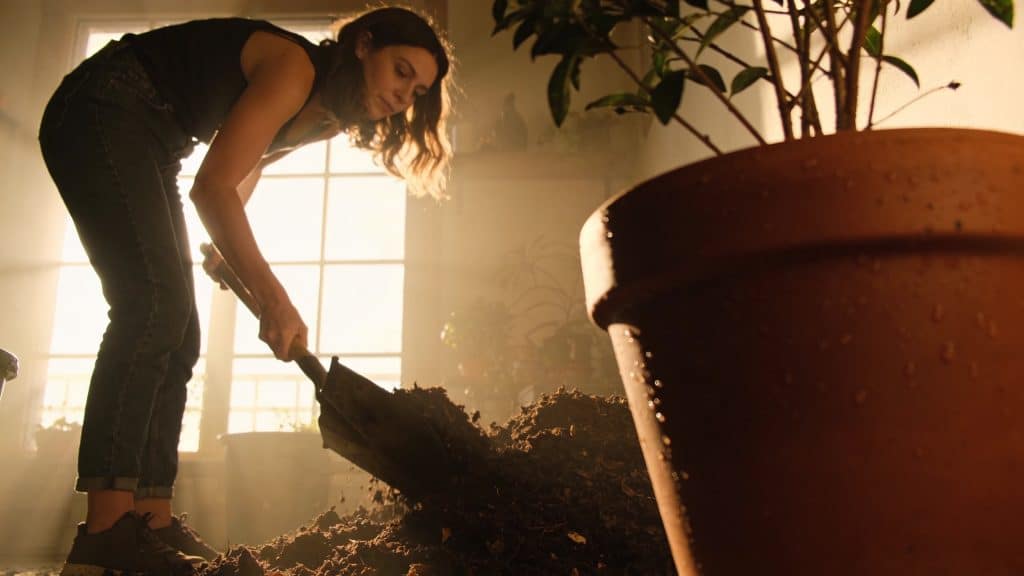 Femme retournant un tas de compost avec une pelle