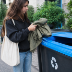 Où jeter les vieux vêtements : trouver les bons points de dépôt Vetements plies pres d'une poubelle de recyclage